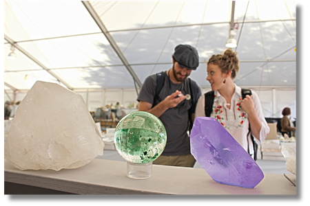 Man and woman examining gems and minerals up close with polished stones in foreground