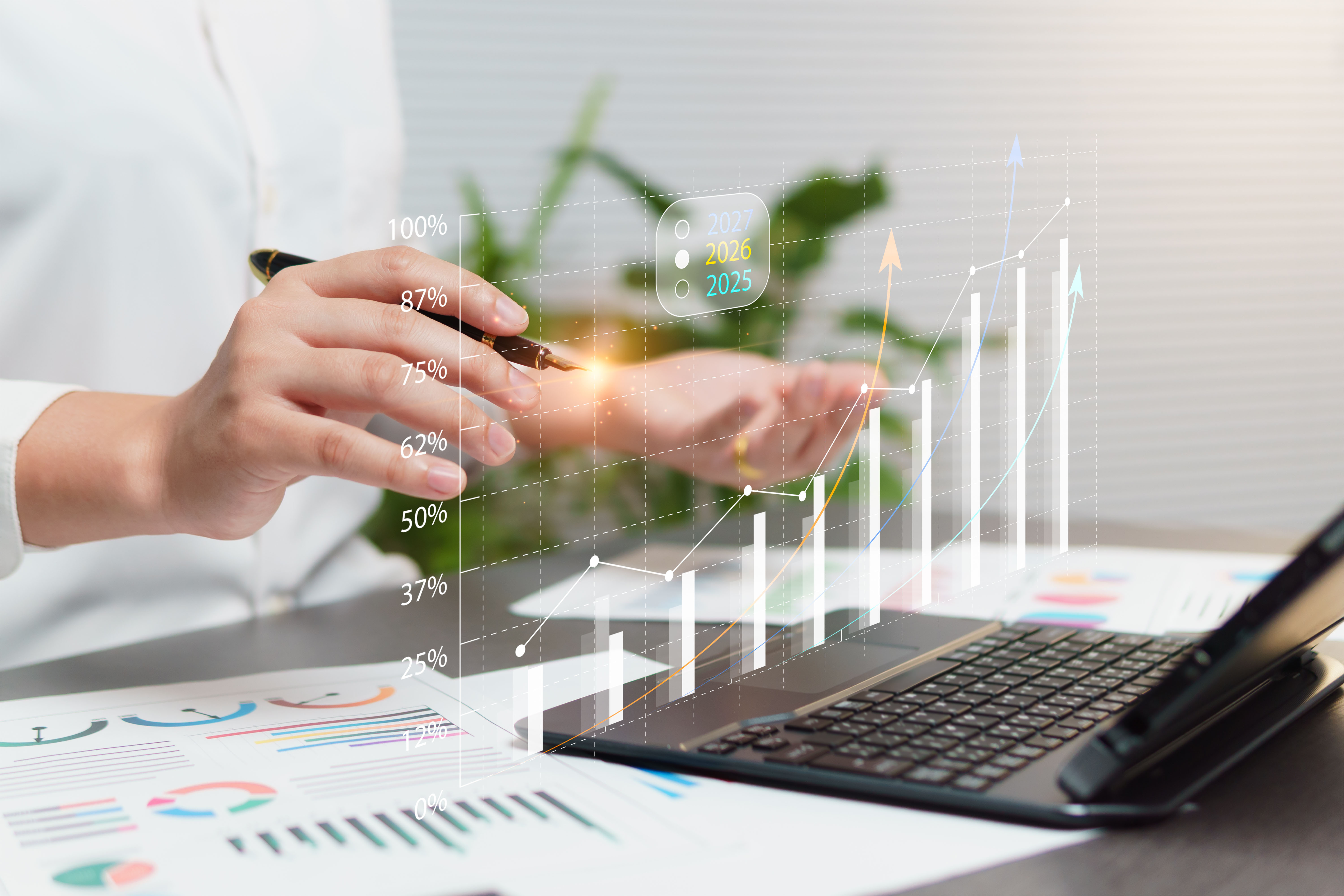 Image of a person working with a pen and a laptop to create a budget calendar
