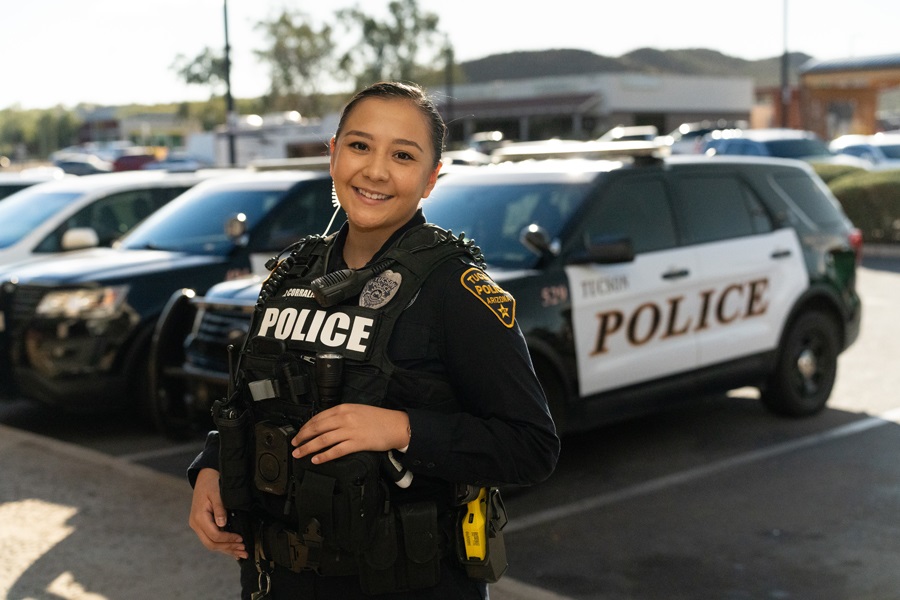 smiling female patrol officer in uniform in front of a patrol vehicle