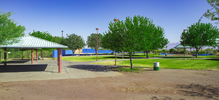 A lush, green grassy field under a clear blue sky, inviting and serene. Large ramada with green roof.